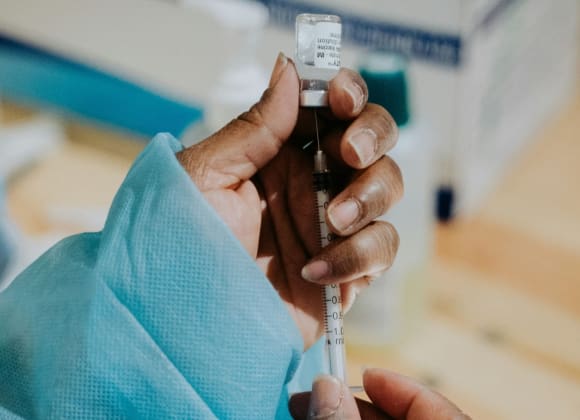 mathurin-napoly-matnapo-ROQwTv9NMPE-unsplash close-up of healthcare professional holding vial and syringe